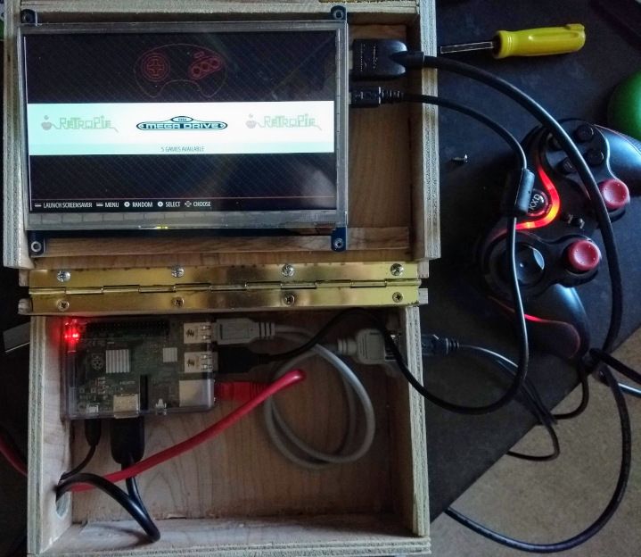 The open box with the Raspberry Pi and 7" screen on.  On the screen is the EmulationStation front graphical interface.