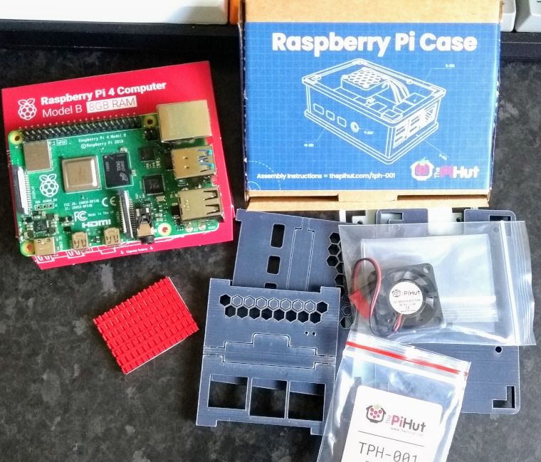 A Raspberry Pi4 B motherboard with a red heat sink and a plastic case, pre-assembly.