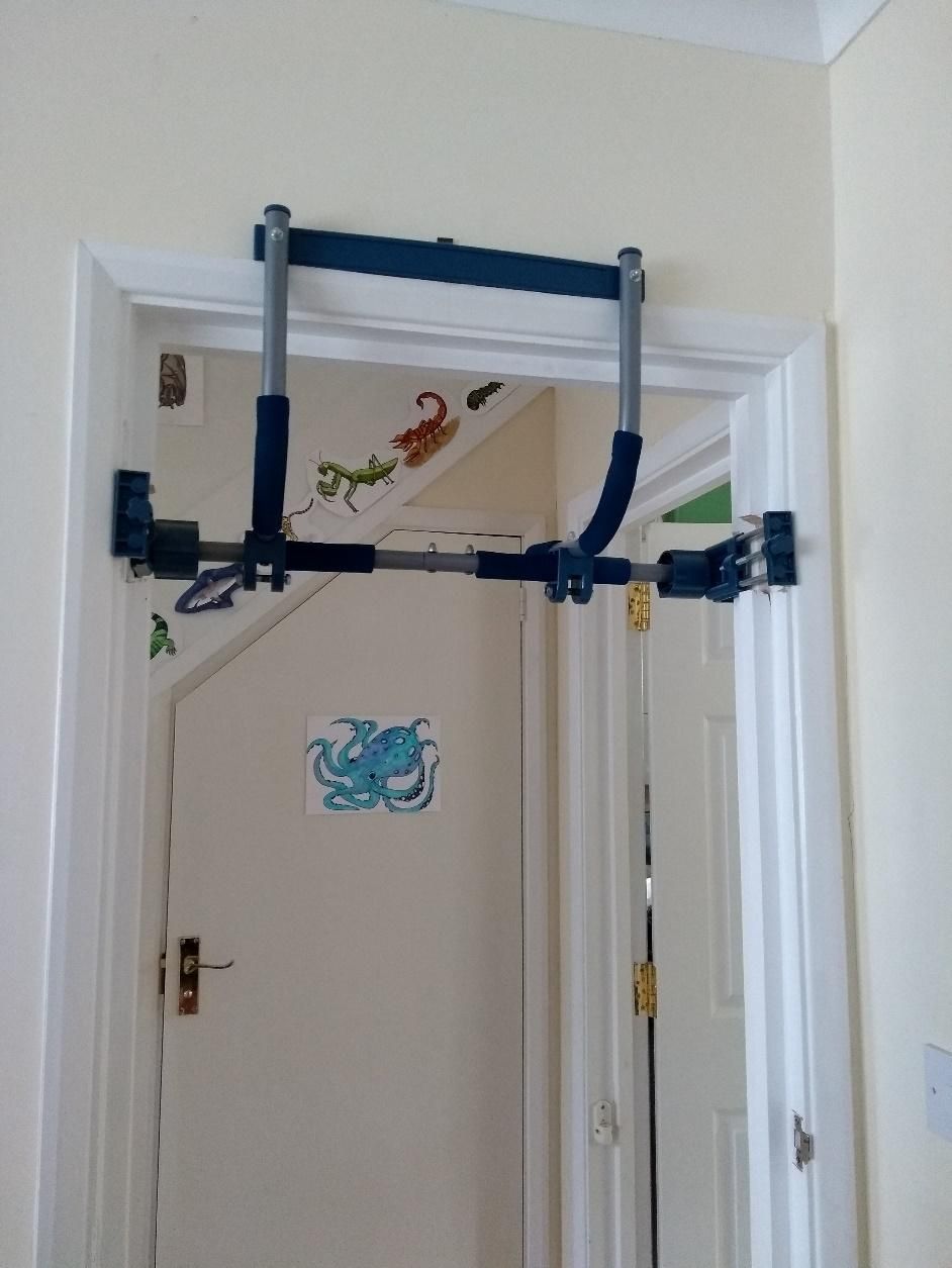 A gym bar / pull up bar in a door way.