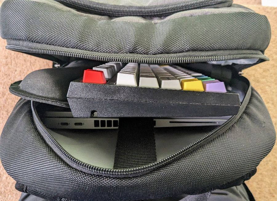 An open rucksack showing a laptop, keyboard, wrist rest, and laptop stand inside.