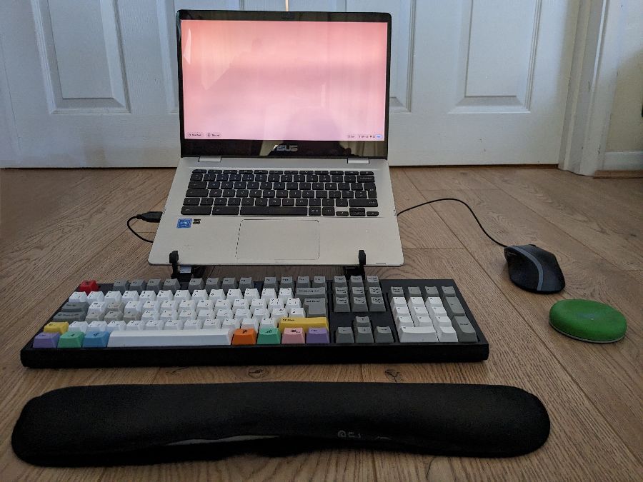 A laptop on a stand, with a keyboard, mouse and wrist rests.