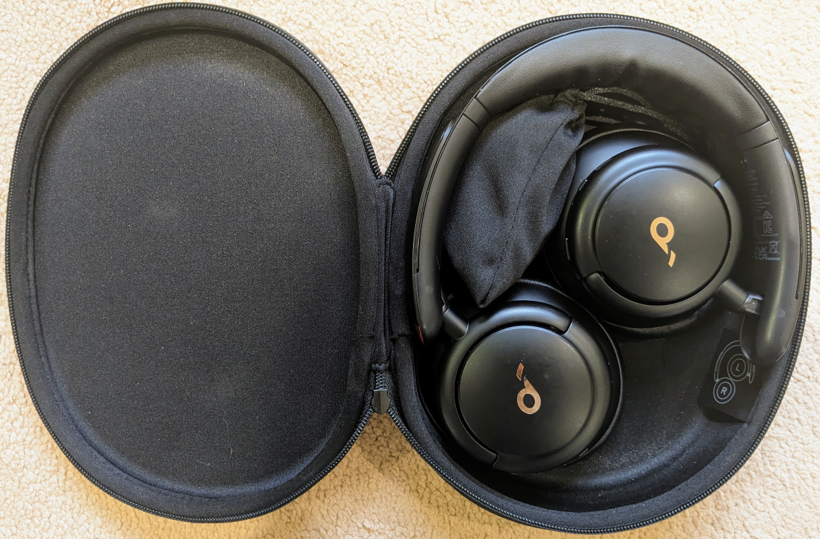 Photograph showing the Q30 headphones in their (open) case.  The drawstring bag with additional cables is tucked inside the headband too.