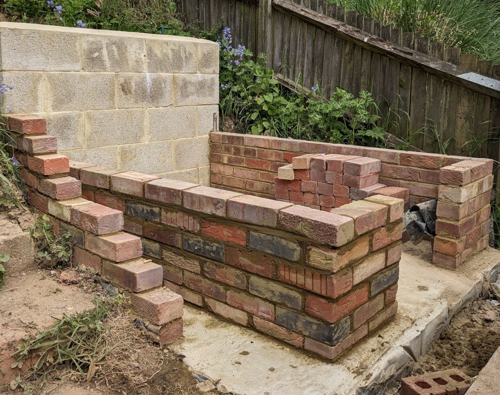 Photograph showing red brick walls, a concrete floor, and a concrete block rear wall.