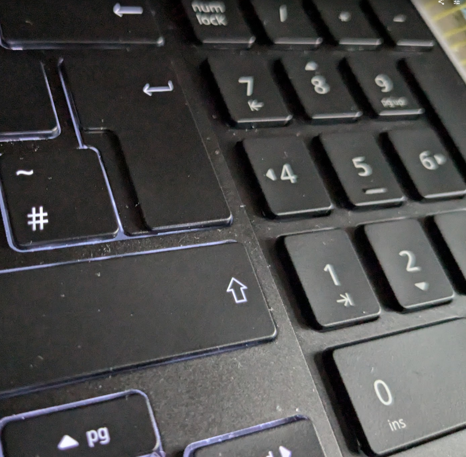 Photo showing the keyboard backlight on, which a lit white outline around the keys, while the number pad is not lit.