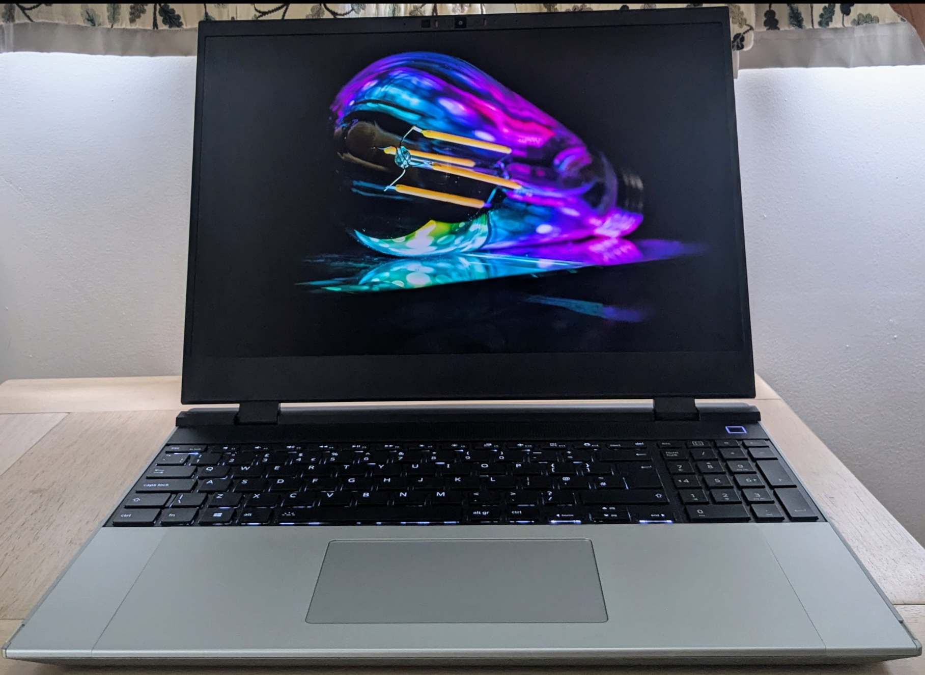 Photograph of the laptop with a photo of a multi-coloured lightbulb full screen.